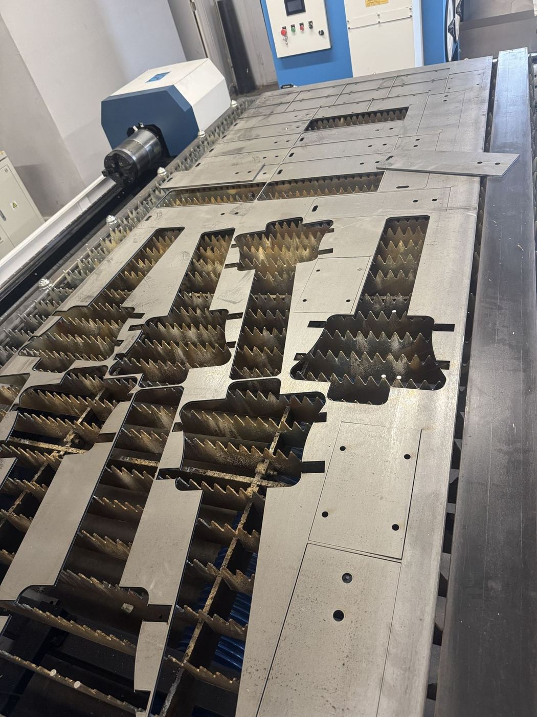 Nested steel sheet of laser-cut parts on RMC's fiber laser bed